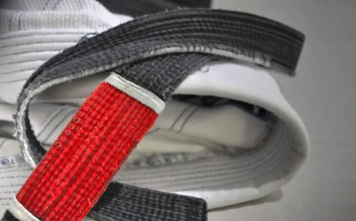 Gros plan sur une ceinture noire de jiu-jitsu brésilien et sa barrette rouge.