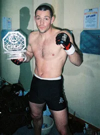 Emmanuel Fernandez en gants de MMA, un trophée à la main, au début des années 2000.